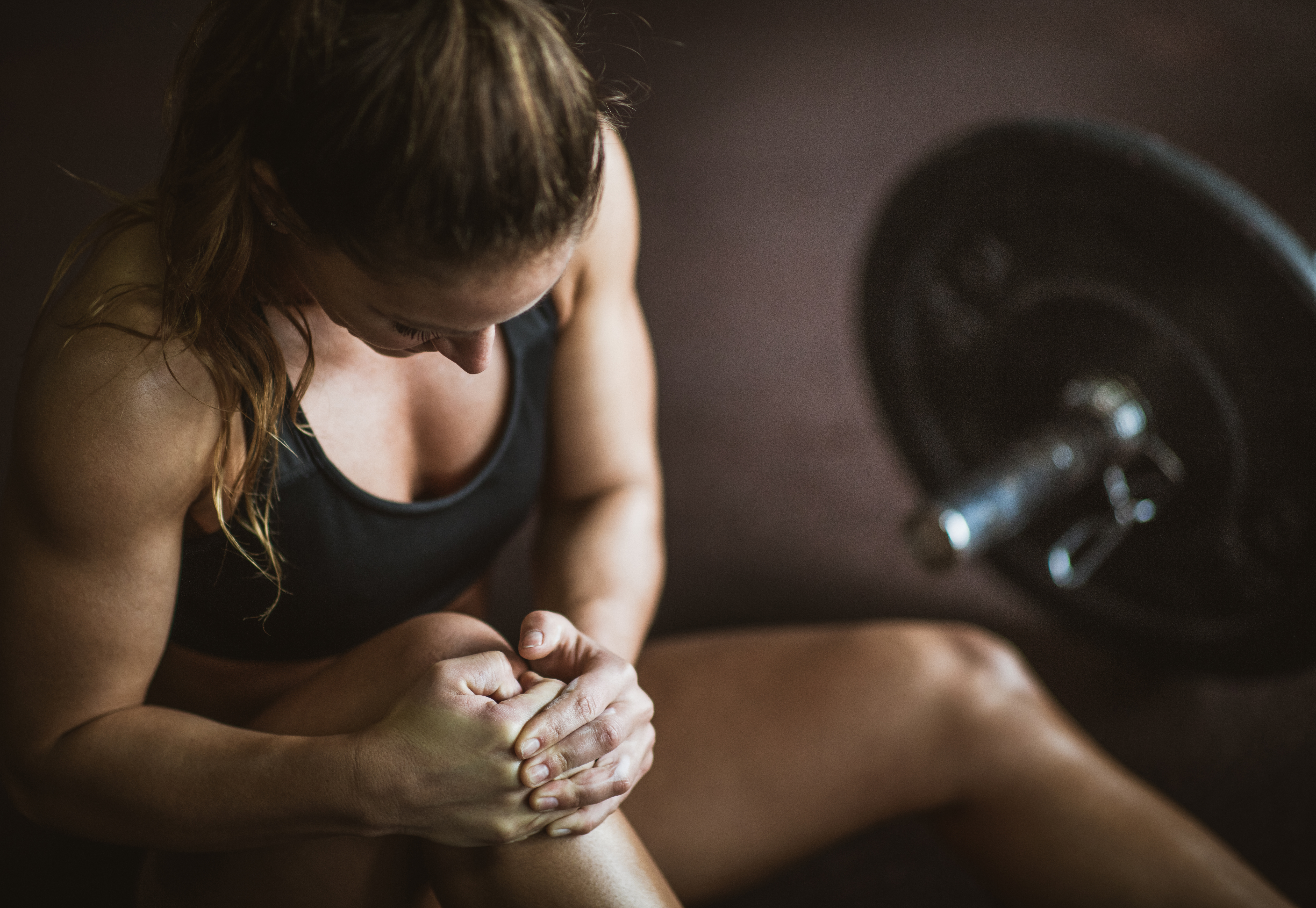 Atletisk kvinna håller om sitt knä i smärta